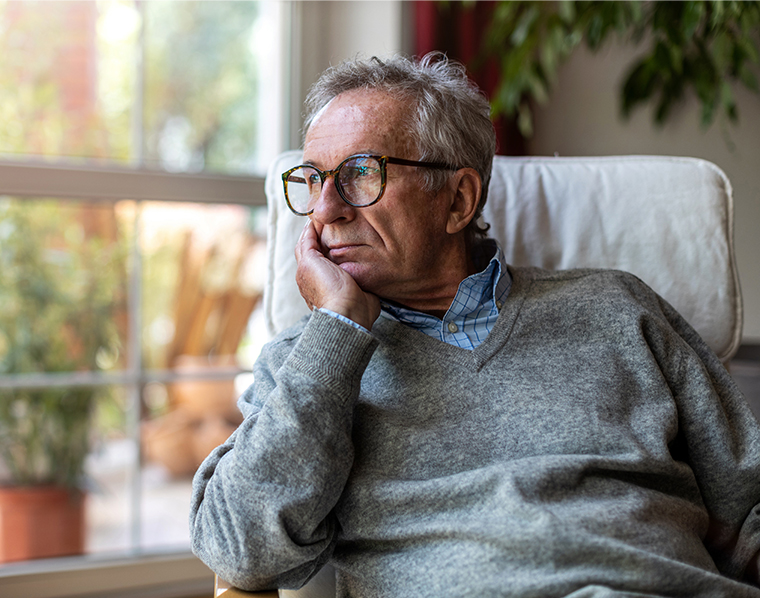 Senior man looking out of window at home